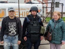 Рятувальник групи "Фенікс" разом з чоловіком та жінкою біля евакомобіля