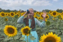 Учасниця конкурсу виконує пісню посеред квітів соняху