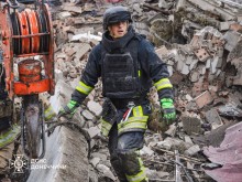 Рятувальник йде до спеціального автомобіля, навкруги каміння після обстрілу.