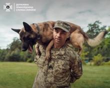 Український прикордонник тримає на плечах службового собаку