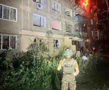 Правоохоронець стоїть біля будівлі, яку зруйнували окупанти