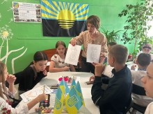 Директор Ценрту «Вогник надії» роздає дітям зображення з державними символами України для виготовлення малюнків