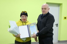 Юрій Винокуров та працівниця ЖКГ, жінка в руках тримає квіти та почесну грамоту.