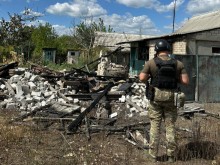 Зруйнований ворожим обстрілом та пожежою будинок поруч з яким стоїть правоохоронець