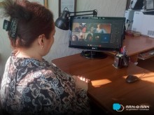 Учасниця онлайн зустрічі сидить біля екрану монітора.