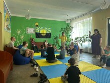 Діти сидять та підіймають руку вгору, беруть участь у грі