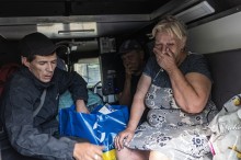 Салон автомобіля.
Чоловіки та жінка з валізами сидять у салоні. Жінка тримає рукою обличчя.
