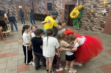 Діти на святковому заході обіймаються з ведучими та між собою