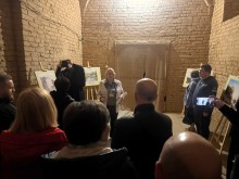 Фахівчиня музею проводить презентацію для аудиторії в історичному приміщенні зі склепінчастою стелею.