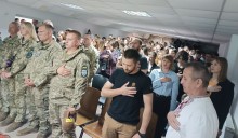 Гімн України звучить у залі, де разом із військовими стоять учні та педагоги. Символ єдності поколінь, гідності та незламності Донеччини.