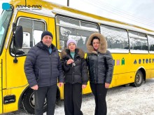 Поруч з автобусом селищний голова Ружинської громади тримає ключі від шкільного автобуса, поруч стоять представники Торецької МВА