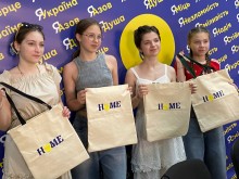 Молодь Маріупольського району Донецької області розмальовувала собі власний шопер на майстер-класах з екосвідомості, дівчата позують з шоперами на фоні банеру