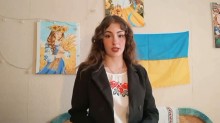 Учасниця конкурсу "Світ українською" у вишиванці на фоні картин і прапора України декламує вірш