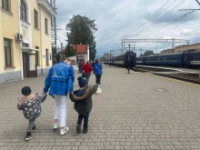 Працівниця "Проліски" веде двох малих дітей на вокзалі