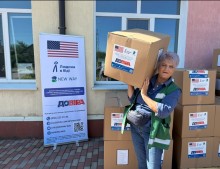 Жінка поруч з коробками з гуманітарною допомогою