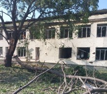 Пошкоджена багатоповерхівка та поламана гілка дерева поруч після ворожого обстрілу.