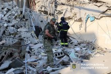 Поліцейський та вибухотехнік біля пошкодженого будинку уважно роздивляють наслідки.