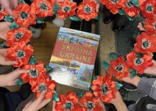 Руки дітей тримають готові вироби у колі навколо книги «Україна»
