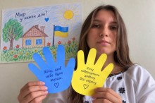 Учасниця акції тримає різнокольорові долоньки