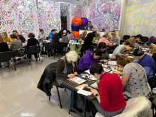 Учасники арттерапії за столами малюють картини