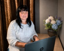 Музейниця Марина Глушко в білій вишиванці під час заходу за ноутбуком