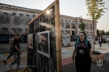 Молода жінка з різнокольоровим волоссям дивиться на фотовиставку фотографа‑документаліста Олега Петрасюка. На фотографіях відображено життя бійців, які захищали місто Часів Яр.