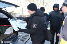 Працівники правоохоронних органів проводять слідчі дії біля автомобіля.