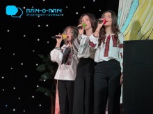 Дівчата на сцені у вишиванках тримають мікрофони та співають.