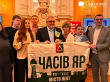 Мер французького міста тримає прапор Часового Яру, поруч стоять діти