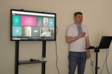 Ведучий заходу співає гімн на фоні екрану з онлайновими учасниками наради
