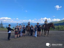 Спільне фото дітей Часовоярської громади. Двоє хлопців сидять на конях. Інші діти підняли руки вгору, ніби тримають небо.