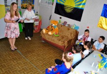 Ведучі розпочинають святковий захід, діти сидять на стільцях