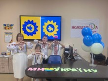 Вчителька та учні у вишиванках складають руками фігуру серця. Поряд напис: "Ми любимо Україну".