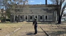 Правоохоронець стоїть на фоні зруйнованого ворогом палацу культури.