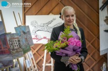 Організаторка та художниця виставки. З букетом яскравих квітів біля своїх картин