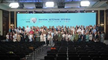Групове фото, зроблене у великій залі. Близько ста людей стоять рядами, дивлячись у камеру. За ними розташований великий екран з написом "Україна. Ветерани. Безпека" та гербом України.