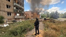 Правоохоронець стоїть біля будівлі, зруйнованої ворожим ударом