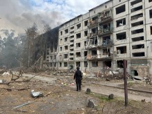 Правоохоронець стоїть біля зруйнованого окупантами багатоквартирного будинку