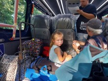 Маленька дівчинка з бабусею сидять в евакуаційному автобусі