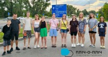 Спільне фото дітей, позаду стоїть дорожній знак зі схемою маршруту.