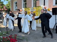 Танцювальний виступ юнаків у чорному одязі та дівчат у білих сукнях на фоні святково прикрашених сходів