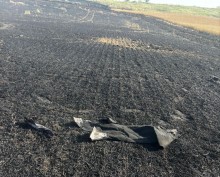 Згоріле поле, майже все чорного кольору. На полі лежать залишки вибухонебезпечних предметів