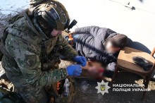 Поранена цивільна людина лежить на землі, поруч пармедик надає першу допомогу.