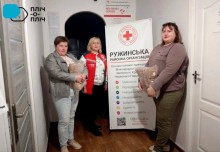 Представниці терцентру отримали для підопічних гуманітарну допомогу від Ружинської районної організації Товариства Червоного Хреста України, фото на фоні банеру