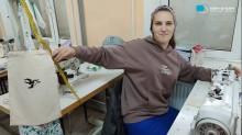 Студентка за швейною машинкою тримає екоторбу з вишивкою