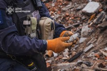 Збільшене фото. Піротехник тримає уламок снаряду.