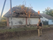 Правоохоронець стоїть біля пошкодженого будинку