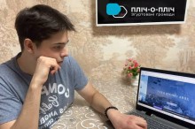 На столі ноутбук, на екрані слайд про Героїв Крут, учень сидить на стільці уважно дивляться.