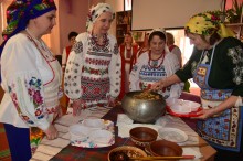 Жінки у народних костюмах готують народні страви.