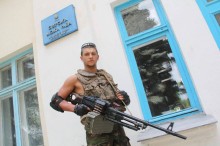 Захисник України у броньованому жилеті з автоматом у руках біля будівлі Сіверської міської ради. Фото 2014 року.
